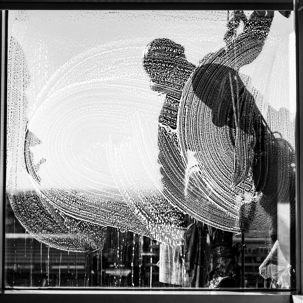 A window cleaner captured against a soapy window in Buenos Aires, Argentina.